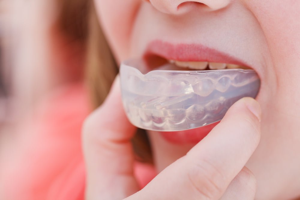 Person placing a clear mouthguard in their mouth
